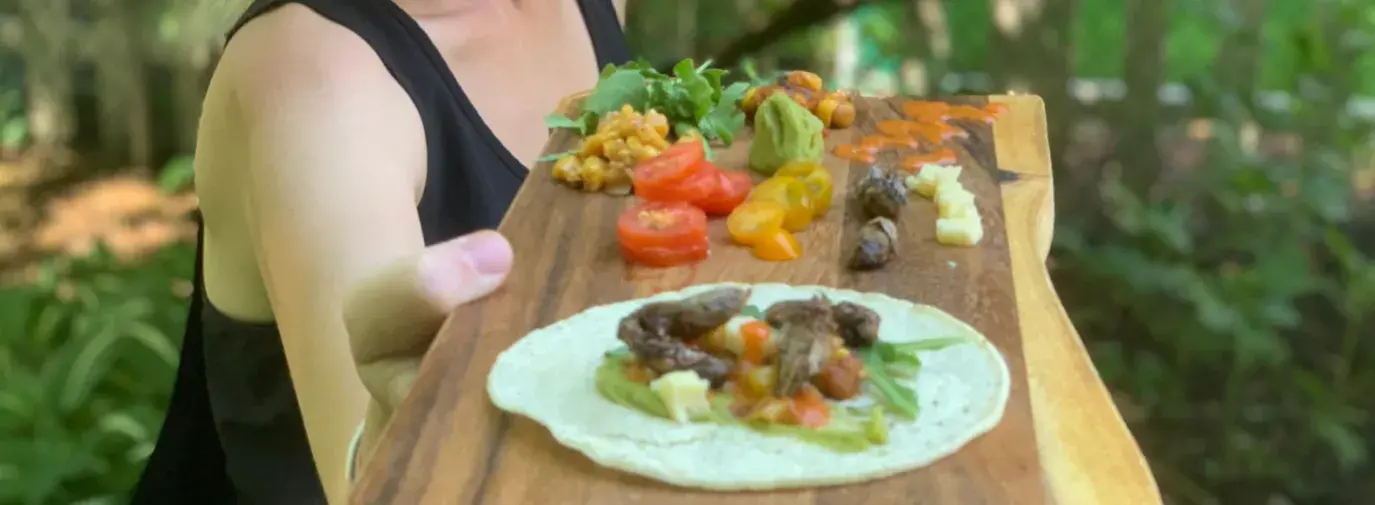 Dr. Cortni Borgerson serves up cicada tacos on a live edge wood cutting board.